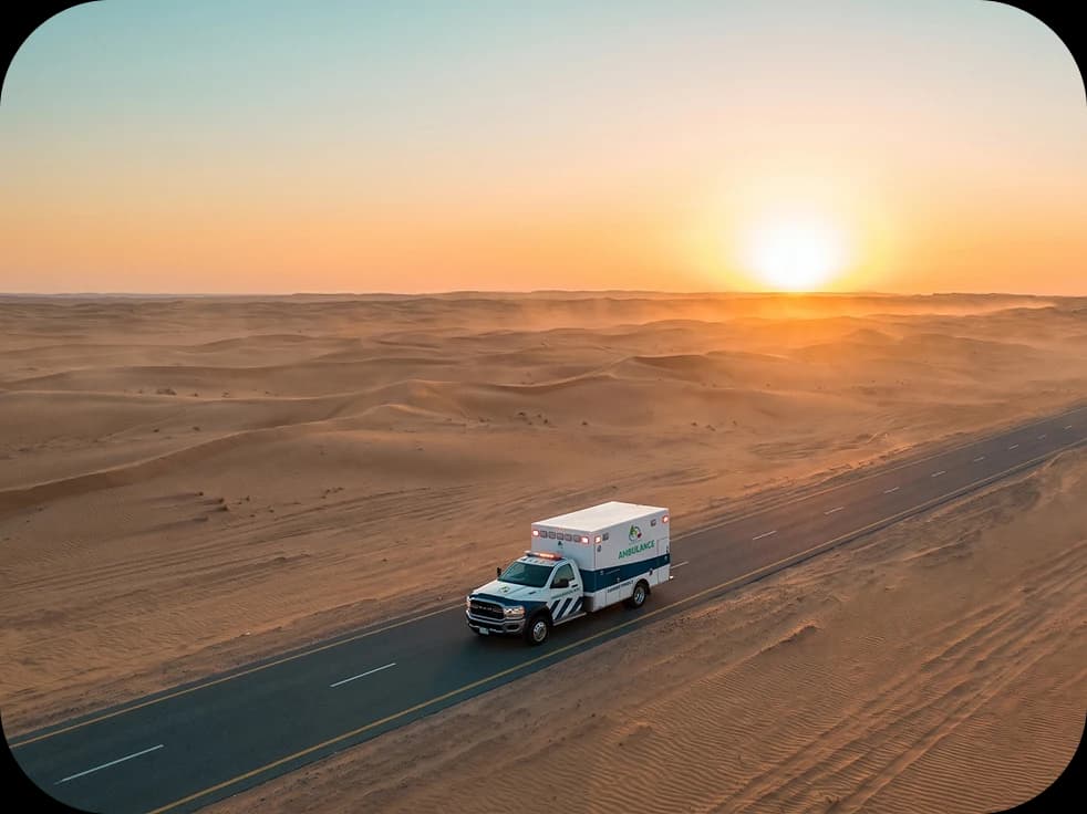 Ambulance driving along a desert highway at sunset
